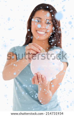 Lovely woman inserting a coin in a piggy bank against snow falling