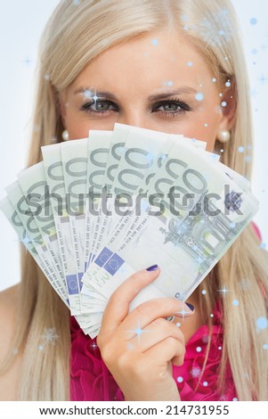 Green eyed woman holding 100 euros banknotes against snow falling
