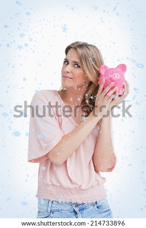 Woman holding a piggy bank up to her head against snow falling