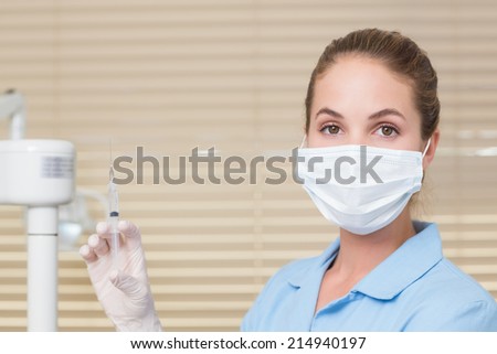 Dental assistant holding injection looking at camera at the dental clinic