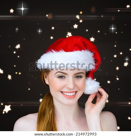 Pretty girl in santa costume smiling at camera against bright star pattern on black
