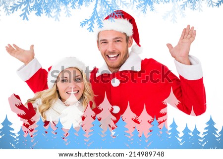 Festive couple smiling with arms raised against frost and fir trees
