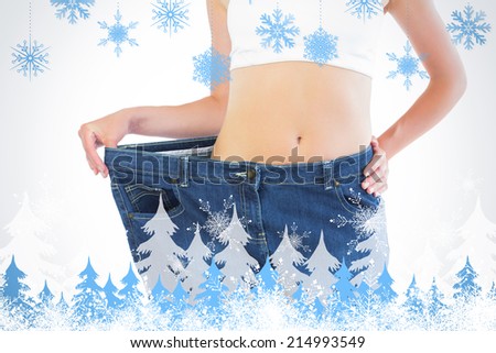 Close up of confident slender blonde wearing too big trousers against snowflakes and fir trees