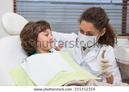 Pediatric dentist showing little boy in chair the drill at the dental clinic