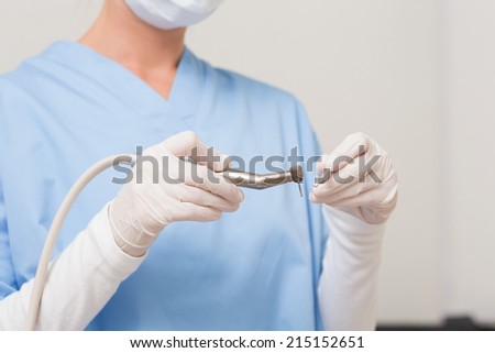 Dentist in blue scrubs holding drill at the dental clinic