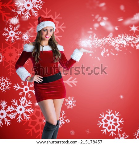Pretty girl in santa costume holding hand out against red snow flake pattern design