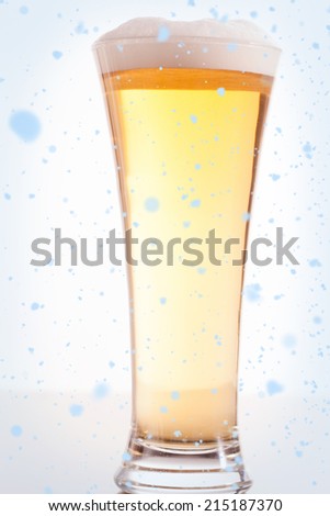 Snow falling against full glass filled with beer and foam