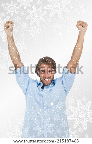 Happy man celebrating success with arms up against snowflakes on silver