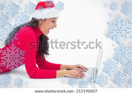 Beautiful festive woman typing on laptop against snowflake frame