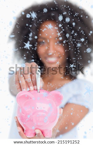 Young woman inserting notes in a piggy bank against snow falling