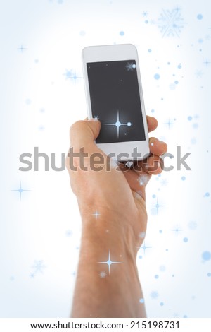 Male hand holding a smartphone against snow falling