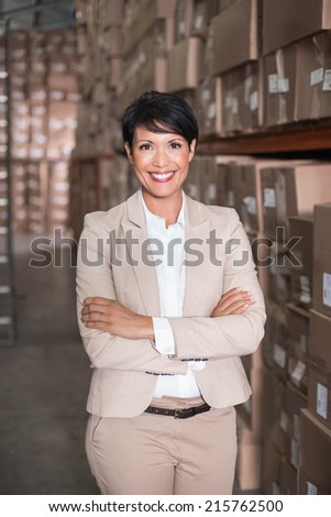 Pretty warehouse manager smiling at camera in a large warehouse