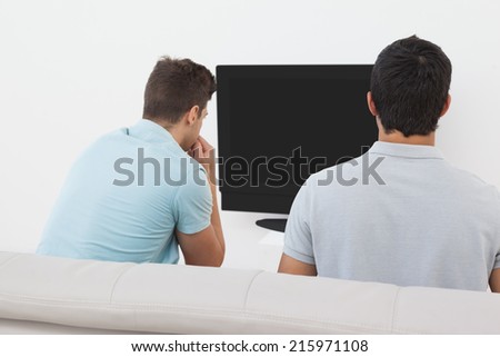 Rear view of two soccer fans watching tv