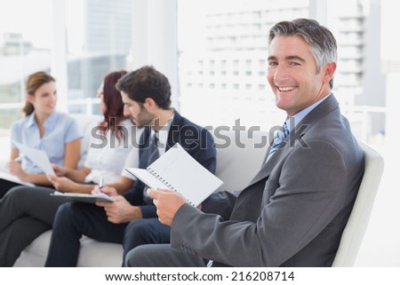 Businessman smiling at the camera with co-workers