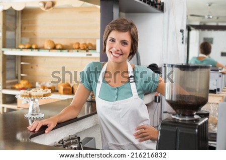 Pretty barista smiling at camera at the coffee shop