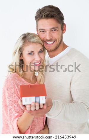 Portrait of attractive young couple holding mini house over white background