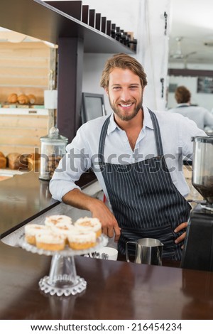 Handsome barista smiling at camera at the coffee shop