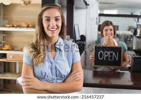 Pretty waitress and customer smiling at camera at the coffee shop