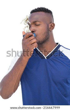Football player kissing winners trophy over white background