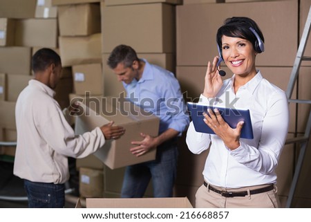 Pretty warehouse manager using tablet during busy period in a large warehouse