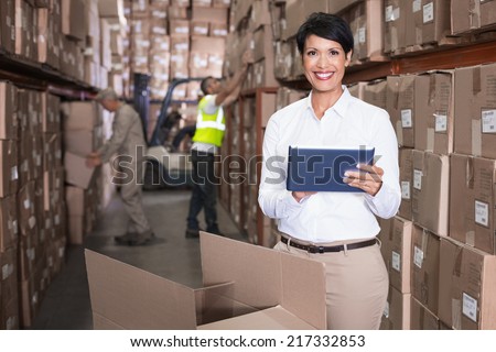 Pretty warehouse manager using tablet pc in a large warehouse
