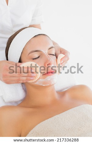 Hand cleaning womans face with cotton swabs at spa center