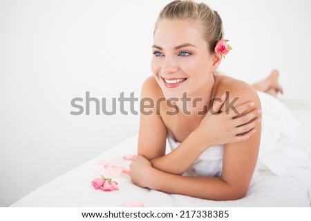 Pretty blonde lying on massage table with petals at the health spa