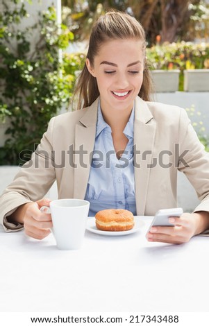 Beautiful businesswoman having a coffee and muffin outside at the coffee shop
