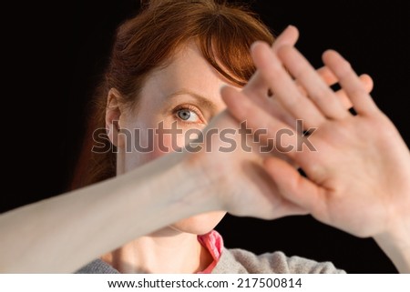 Scared woman covering her face on black background