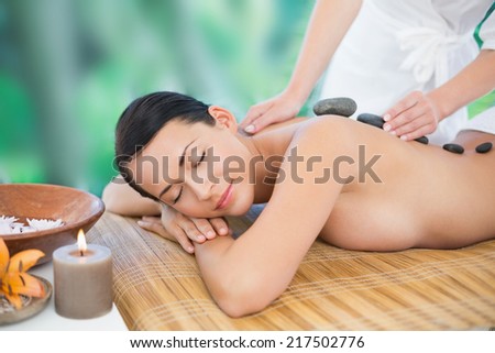 Beautiful brunette enjoying a hot stone massage at a luxury spa