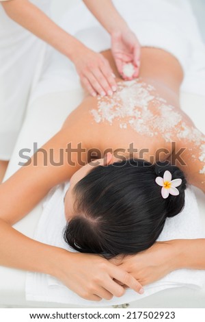 Peaceful brunette getting a salt scrub beauty treatment in the health spa