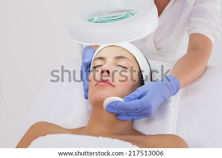 Hands cleaning womans face with cotton swabs at spa center