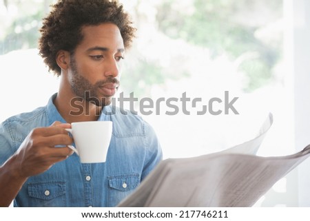 Casual man having coffee while reading newspaper at the coffee shop
