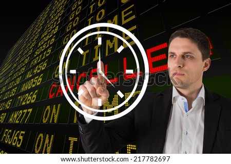 Businessman standing and pointing to a white clock against black airport departures board