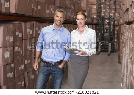 Warehouse team working together with clipboard in a large warehouse