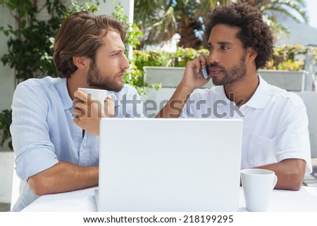 Two friends enjoying coffee together with laptop outside at the coffee shop