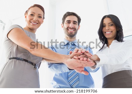 Workers with stacked hands smiling together