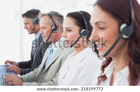 Call center workers wearing headsets and using computers