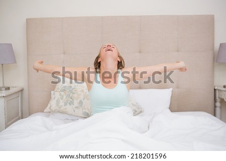 Happy blonde waking up in bed at home in the bedroom