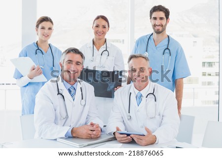 Doctors smiling at the camera as they have a meeting