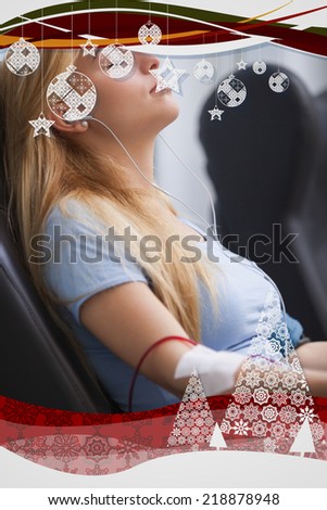 Woman donating blood and listening to music device against christmas frame