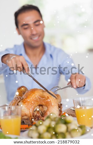 Composite image of man carving turkey at head of table against snow falling