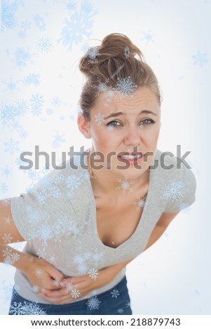 Young woman suffering from stomach pain against snow falling