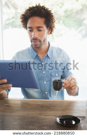 Casual man having coffee while using tablet at the coffee shop
