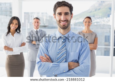 Smiling businessman and his co-workers standing behind
