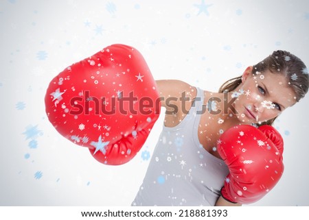 Composite image of serious woman boxing against snow falling