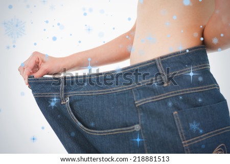 Close up of a woman belly in too big pants against snow falling
