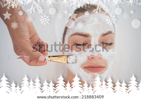 Beautiful blonde getting a facial treatment against fir tree forest and snowflakes