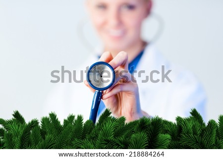 Doctor holding out stethescope with focus on object against digitally generated fir tree branches