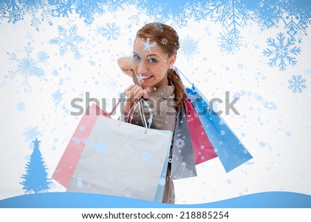Side view of smiling woman with shopping bags against snow flake frame in blue